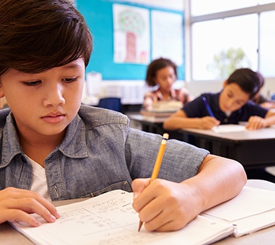 Schoolboy working at desk in test conditions